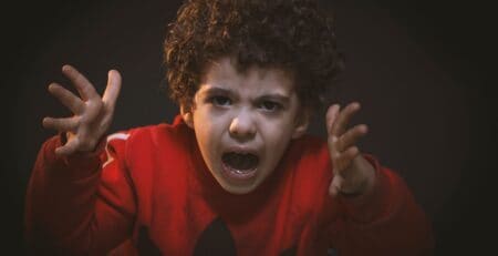 Angry child with curly hair expressing frustration and distress.